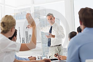 Senior businessman presenting bar chart to his colleagues asking questions