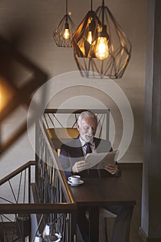 Senior businessman reading newspaper and drinking coffee