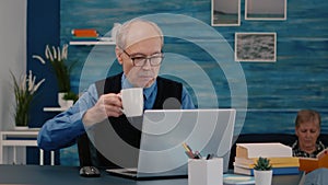 Senior businessman reading reports sitting in front of laptop