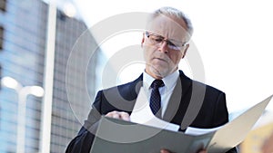 Senior businessman with ring binder folder in city