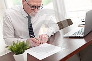 Senior businessman signing a document (Lorem ipsum text used)