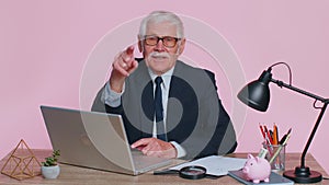 Senior businessman smiling pointing to camera, choosing lucky winner, indicating to awesome you