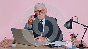 Senior businessman smiling pointing to camera, choosing lucky winner, indicating to awesome you