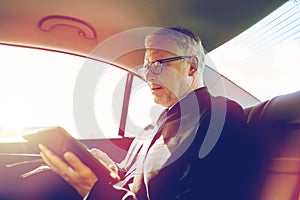 Senior businessman with tablet pc driving in car