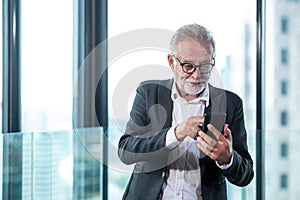 Senior businessman using smart phone communication him work.  People retire check data stock market on smartphone for investment.