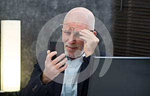 Senior businessman using smartphone, he is having difficulties and vision problems