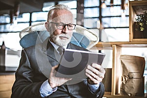 Senior businessman working on digital tablet. Close up.