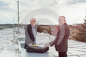 Senior businessmen making a business deal on the roof of a build