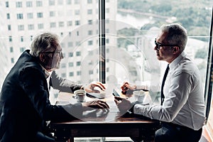 Senior businessmen sitting and working together at coffee shop