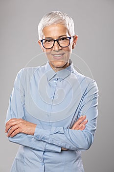Senior businesswoman with glasses in a blue shirt and gray white hair and glasses