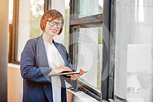 Senior businesswoman with laptop near the window