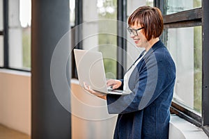 Senior businesswoman with laptop near the window