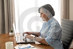 Senior businesswoman typing on a laptop from home