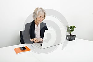 Senior businesswoman using laptop at desk in office