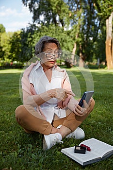 Senior businesswoman using mobile to solve problem while rest in park