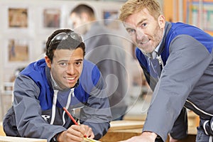 senior carpenter and apprentice measuring wood