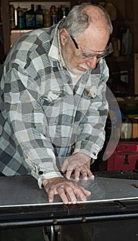 Senior carpenter with goggles cutting on circular saw