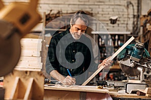 Senior carpenter holding a plank