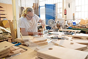Senior carpenter working on wood craft at workspace producing wooden furniture.