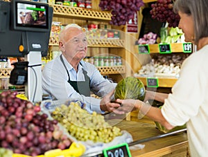 Senior cashier serving customer in greengrocer photo