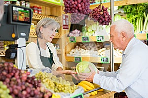 Senior cashier woman serving customer in greengrocer