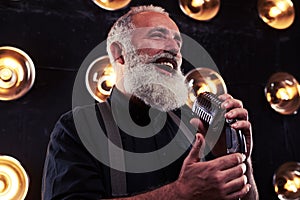 A senior Caucasian bearded man with microphone singing jazz