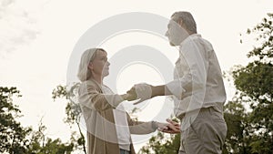 Senior Caucasian couple dancing in park. With a happy smile, feel relax with nature in the morning. Or in the evening. Is a family