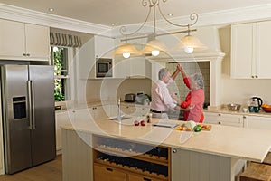 Senior caucasian couple dancing together and smiling in kitchen