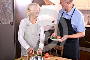 senior caucasian couple having fun in kitchen with healthy food, cooking meal at home