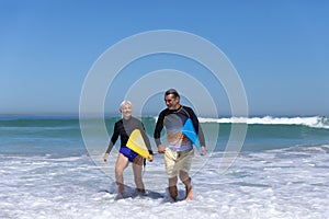 Senior Caucasian couple holding surfboards at the beach.