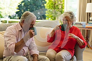 Senior caucasian couple sitting on sofa together drinking coffee in living room