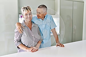 Senior caucasian couple smiling happy and hugging standing at the kitchen
