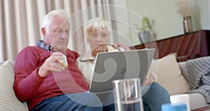 Senior caucasian couple using laptop for online doctor consultation at home, slow motion