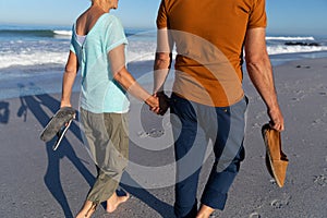 Senior Caucasian couple walking at the beach.