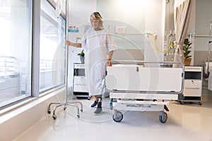 Senior caucasian female patient with prosthetic leg holding drip in patient room at hospital