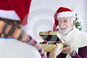 Senior caucasian grandfather giving christmas present to the family member for celebrating Christmas together in happiness and