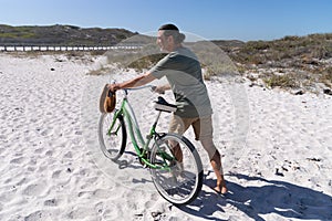 Senior Caucasian man carrying a bike at the beach