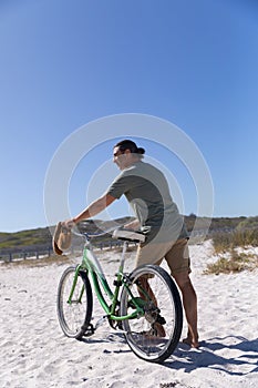 Senior Caucasian man carrying a bike at the beach