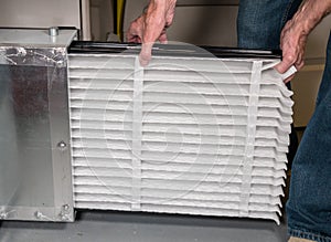 Senior man inserting a new air filter in a HVAC Furnace