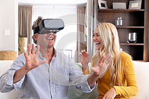 Senior Caucasian man and his adult daughter using a VR headset at home