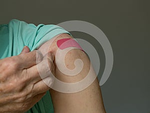 Senior man holding up shirt after covid-19 vaccine injection