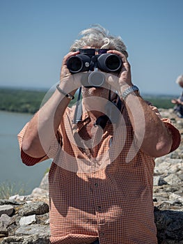 Senior caucasian man looking through binoculars and observe landscape