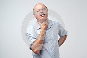 Senior caucasian man in shirt having pain in throat. Flu or other illness in cold winter.