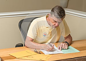 Senior caucasian man sitting at his desk and completing absentee voting ballot