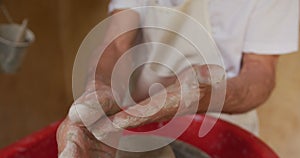 Senior caucasian man wearing apron and cleaning hands in pottery workshop