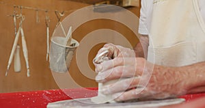 Senior caucasian man wearing apron and forming pottery in pottery workshop