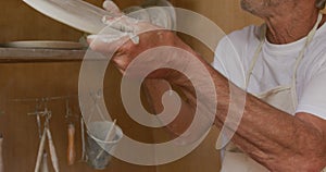 Senior caucasian man wearing apron making dish in pottery workshop