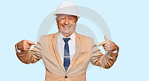 Senior caucasian man wearing architect hardhat looking confident with smile on face, pointing oneself with fingers proud and happy
