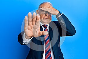 Senior caucasian man wearing business suit and tie covering eyes with hands and doing stop gesture with sad and fear expression