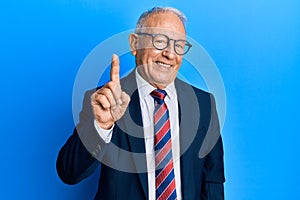 Senior caucasian man wearing business suit and tie pointing finger up with successful idea